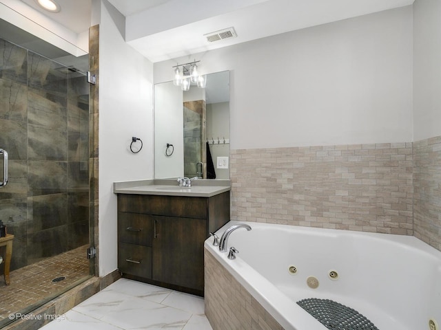 bathroom featuring marble finish floor, a tub with jets, a stall shower, and vanity