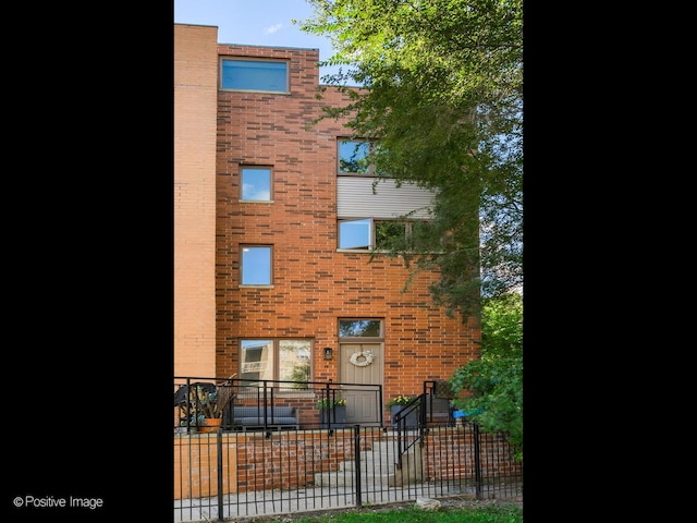 view of front of house featuring brick siding and fence