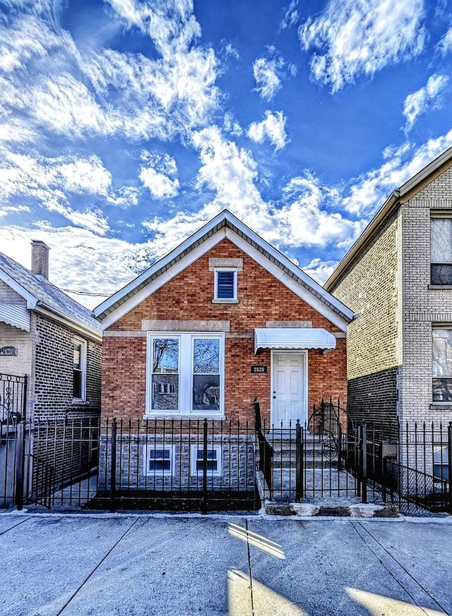 bungalow-style home with a fenced front yard and brick siding