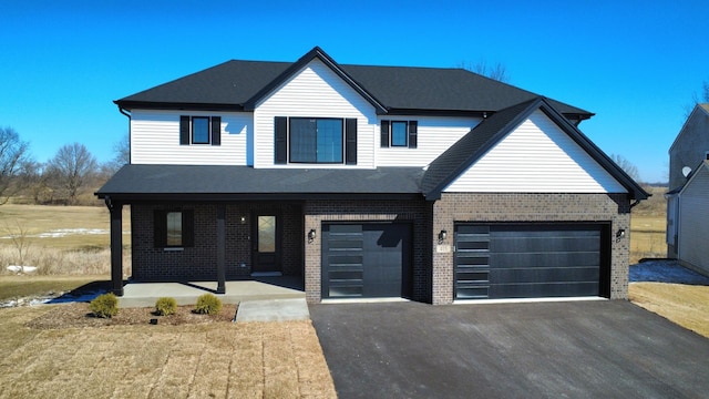 view of front facade featuring brick siding, covered porch, driveway, and an attached garage