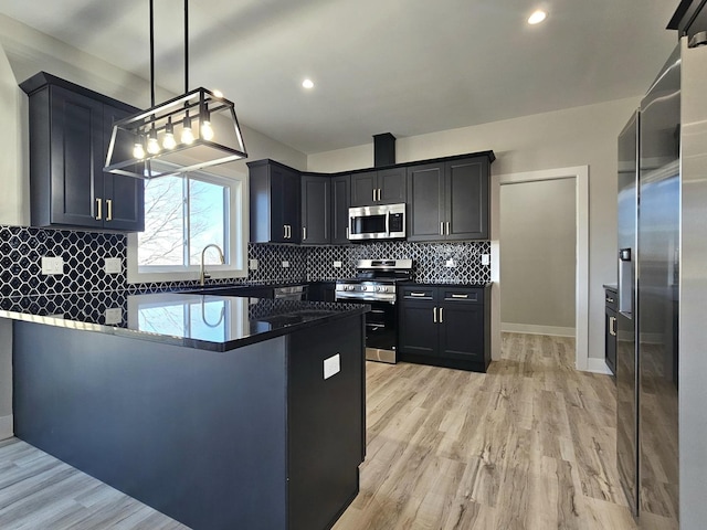 kitchen featuring a peninsula, stainless steel appliances, dark countertops, tasteful backsplash, and light wood-type flooring