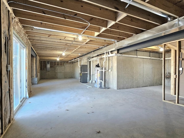 unfinished basement with electric panel, heating unit, and water heater