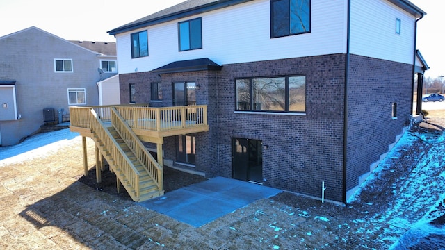 rear view of house with central air condition unit, stairway, brick siding, and a wooden deck