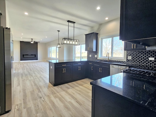 kitchen with a peninsula, a fireplace, stainless steel appliances, tasteful backsplash, and open floor plan