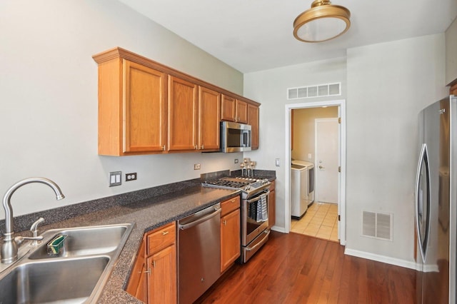 kitchen featuring appliances with stainless steel finishes, visible vents, independent washer and dryer, and a sink