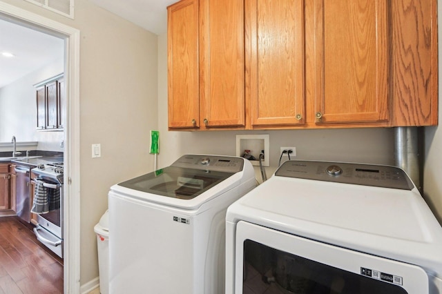 clothes washing area featuring washer and dryer, cabinet space, dark wood-style flooring, a sink, and visible vents