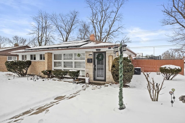 view of front of property featuring fence, brick siding, and a chimney