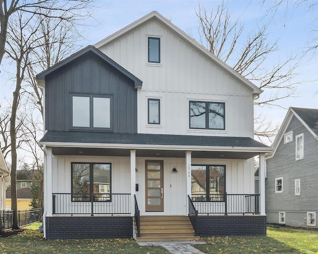 modern inspired farmhouse featuring covered porch, board and batten siding, and roof with shingles