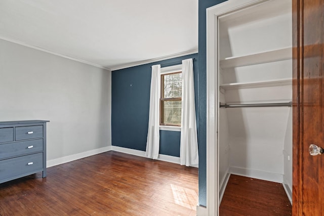 unfurnished bedroom featuring a closet, ornamental molding, baseboards, and dark wood-style flooring