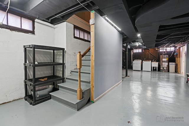 below grade area featuring washer and dryer, gas water heater, stairs, and a sink