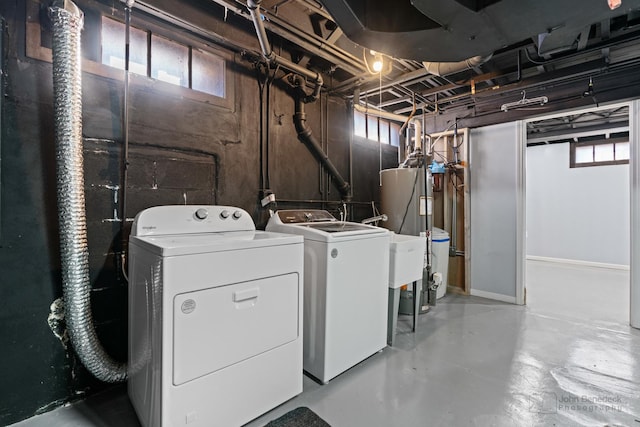 clothes washing area featuring washer and dryer, laundry area, and water heater