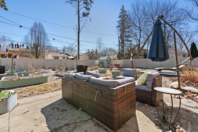 view of patio with an outbuilding, a garden, a fenced backyard, and an outdoor hangout area