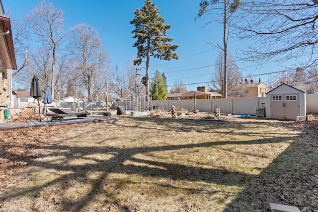 view of yard featuring a storage shed, a fenced backyard, an outdoor structure, and a patio area