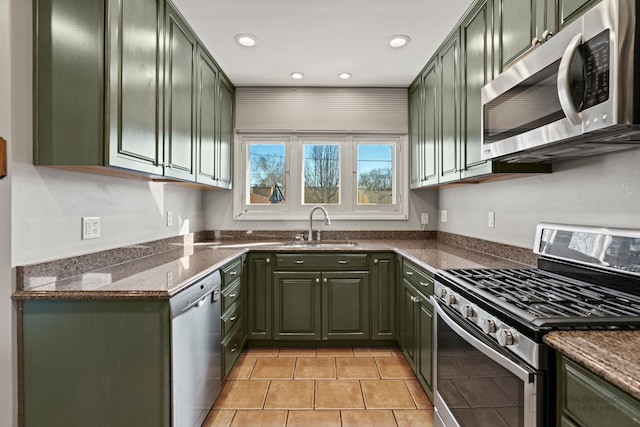 kitchen with a sink, dark stone counters, appliances with stainless steel finishes, and green cabinets