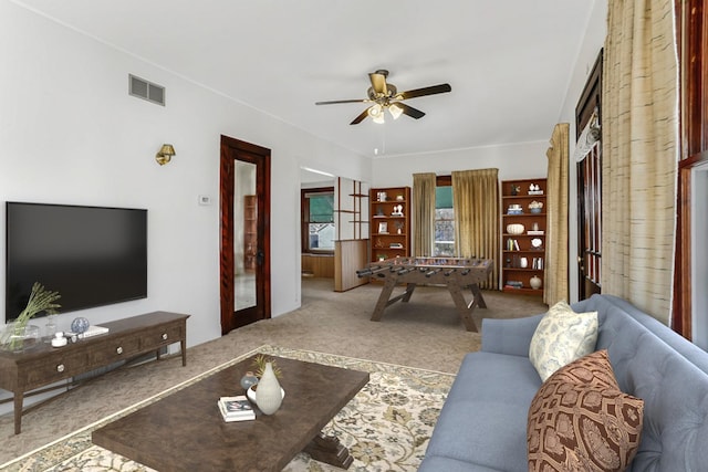 living area featuring carpet, visible vents, and ceiling fan