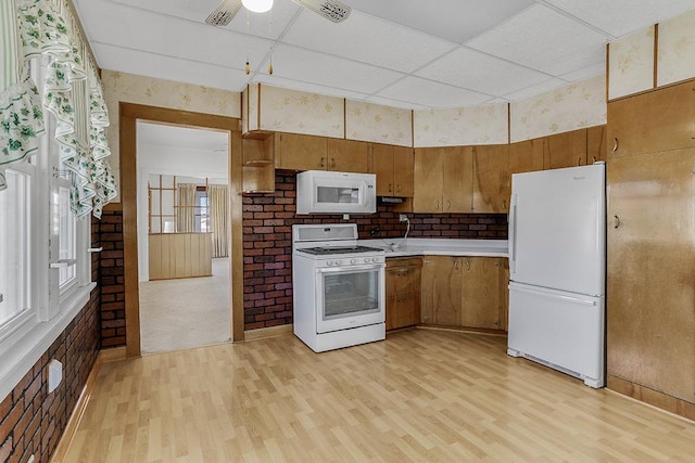 kitchen featuring light wood-type flooring, a paneled ceiling, white appliances, and light countertops