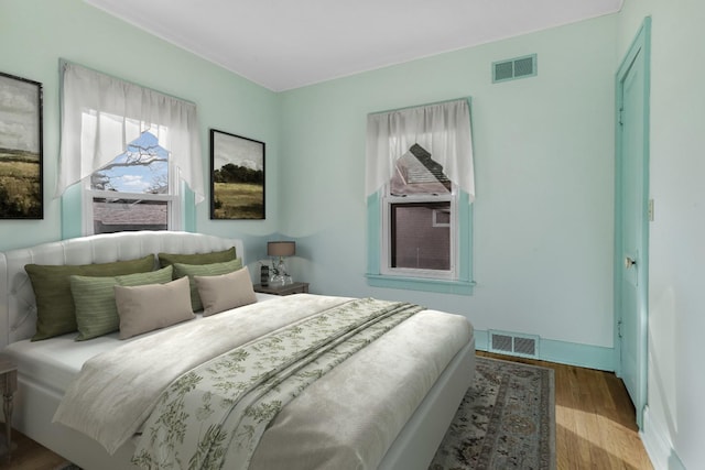 bedroom featuring visible vents, baseboards, and wood finished floors