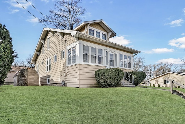 view of front of home with a front yard, an outbuilding, and a sunroom