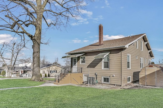 back of property featuring an outbuilding, a yard, and a chimney