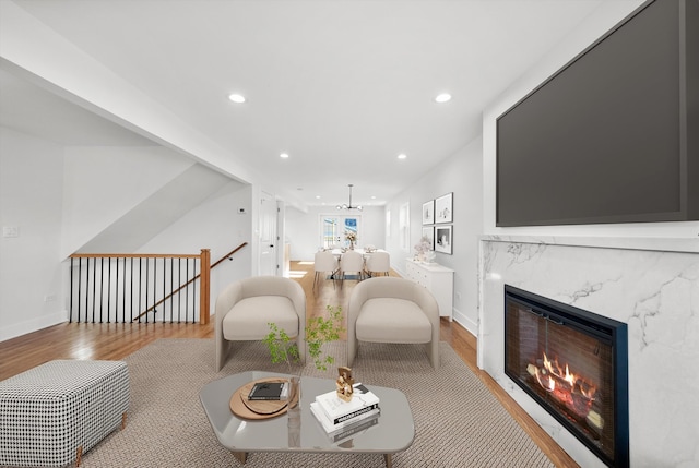 living area featuring a premium fireplace, recessed lighting, baseboards, and wood finished floors