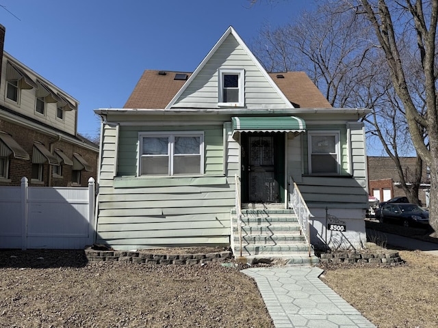 bungalow with a shingled roof and fence