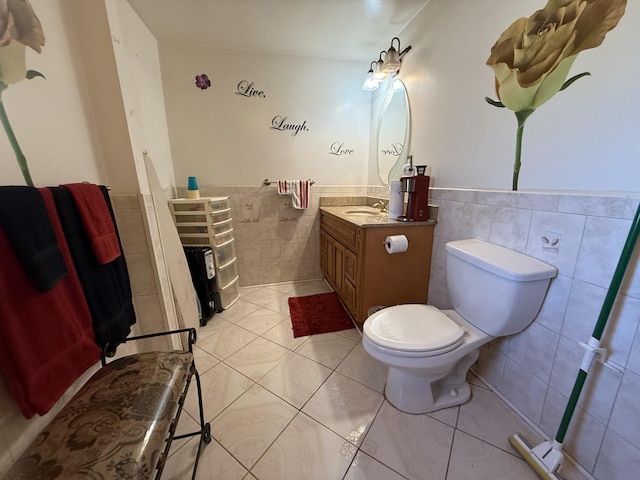 bathroom with a wainscoted wall, toilet, tile walls, tile patterned flooring, and vanity