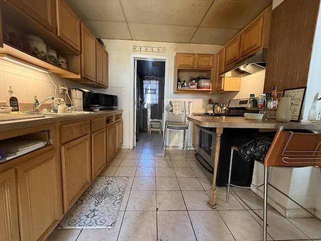 kitchen featuring under cabinet range hood, light tile patterned floors, stainless steel appliances, and open shelves