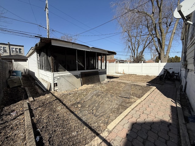 view of side of property featuring a fenced backyard and a sunroom