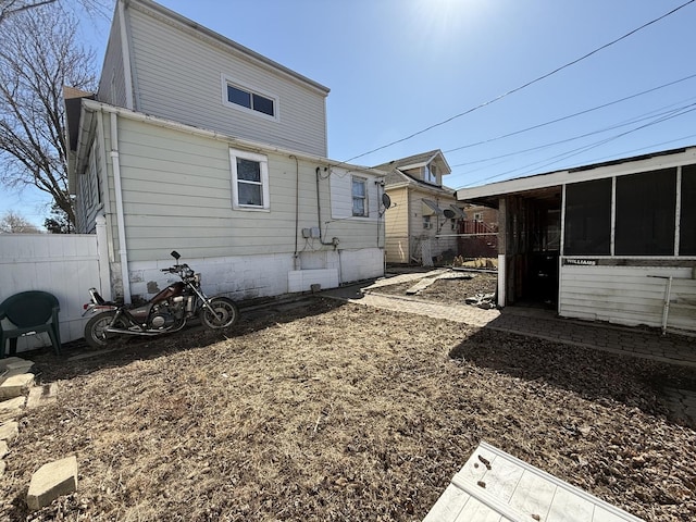 rear view of property featuring fence and a sunroom