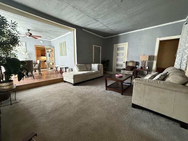 carpeted living room featuring ornamental molding and a ceiling fan