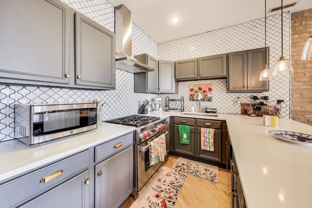 kitchen featuring visible vents, a sink, backsplash, appliances with stainless steel finishes, and wall chimney range hood