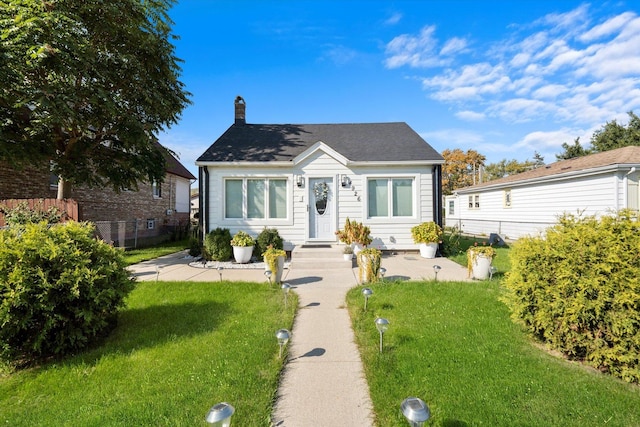 bungalow with a front yard, fence, and a chimney