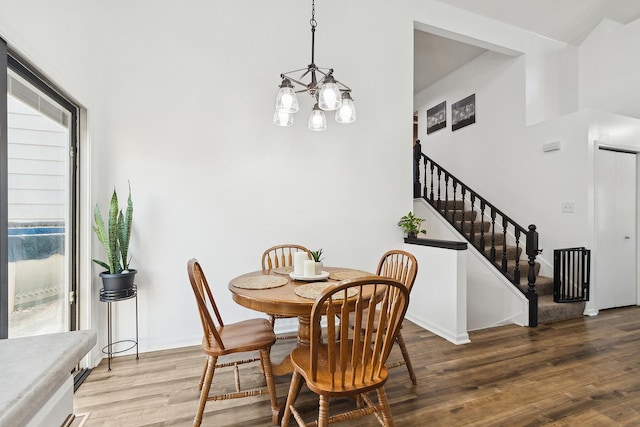 dining area featuring stairway, a notable chandelier, wood finished floors, and baseboards