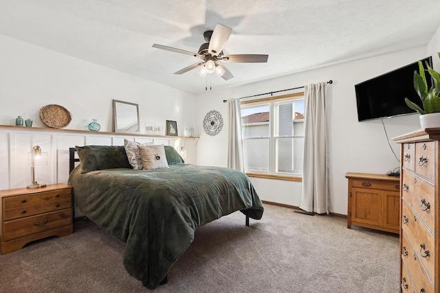 bedroom with a textured ceiling, ceiling fan, baseboards, and light carpet