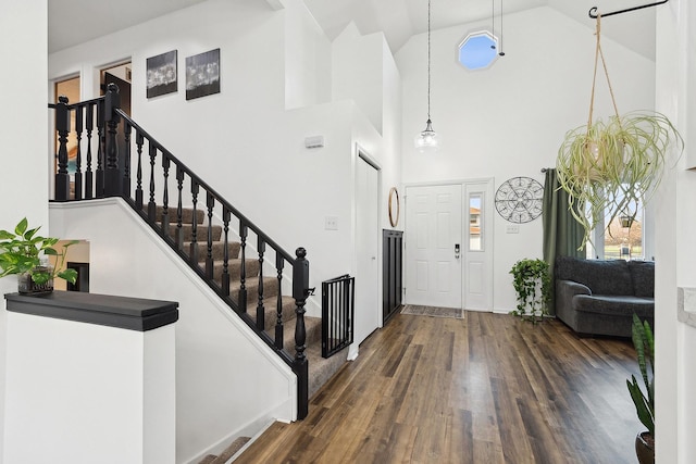 entrance foyer featuring high vaulted ceiling, stairs, and wood finished floors