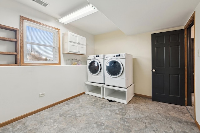 washroom with visible vents, baseboards, cabinet space, and washer and clothes dryer