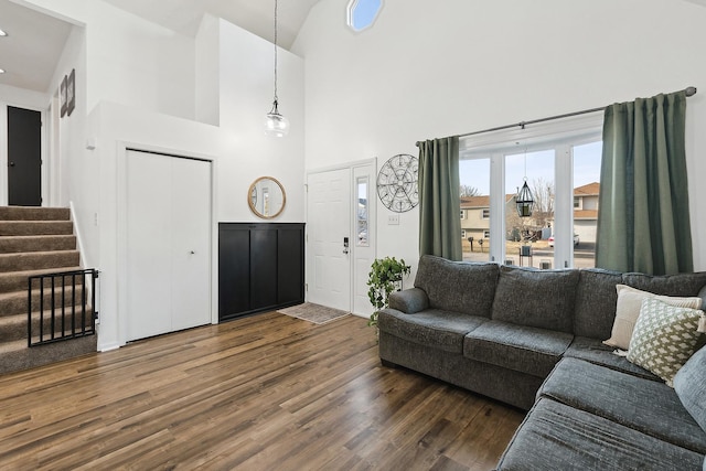 living area featuring stairway, high vaulted ceiling, and dark wood-type flooring