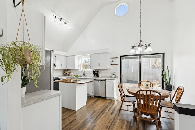 kitchen featuring dark wood-type flooring, a sink, stainless steel dishwasher, tasteful backsplash, and a center island