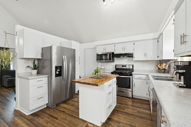 kitchen featuring wooden counters, a sink, under cabinet range hood, appliances with stainless steel finishes, and backsplash