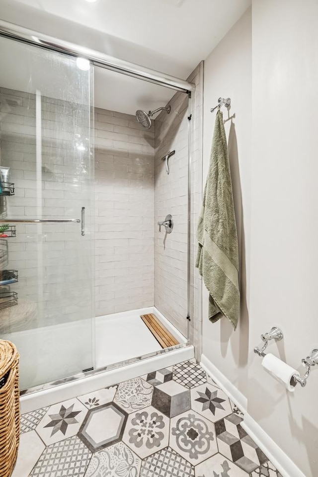 full bathroom featuring tile patterned floors, baseboards, and a stall shower