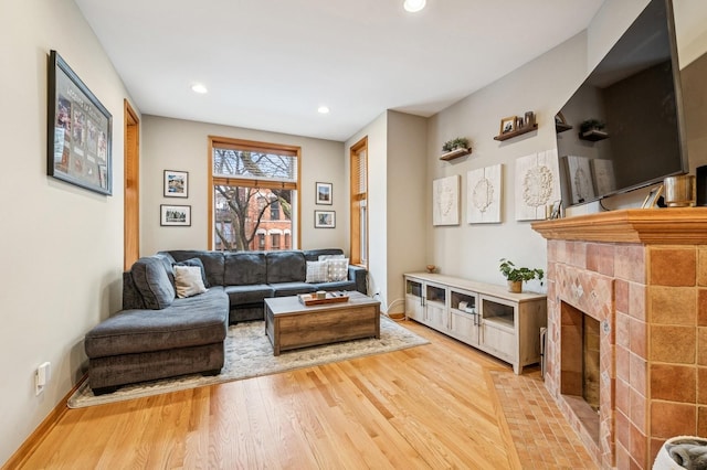 living area featuring recessed lighting, a tile fireplace, baseboards, and wood finished floors