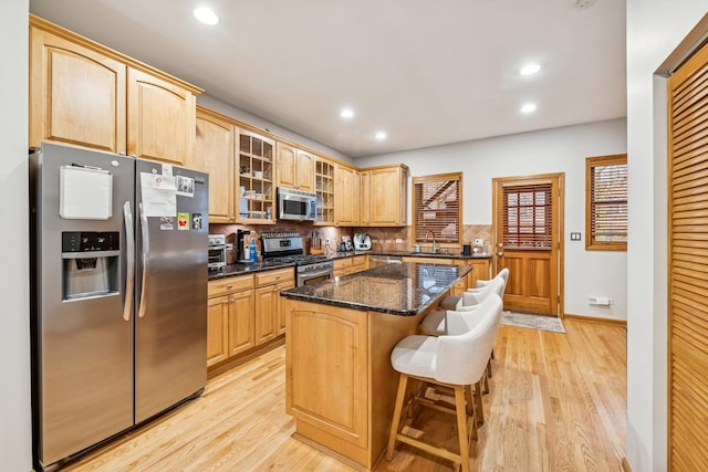 kitchen featuring backsplash, light wood-style flooring, stainless steel appliances, and glass insert cabinets