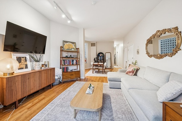 living area with track lighting, visible vents, and light wood finished floors