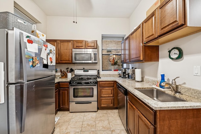 kitchen featuring light tile patterned flooring, brown cabinets, appliances with stainless steel finishes, and a sink