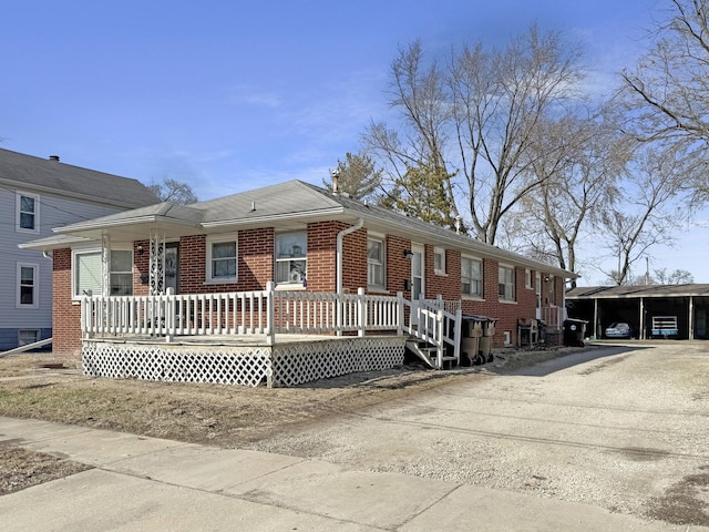 ranch-style house featuring brick siding, a porch, driveway, and a carport