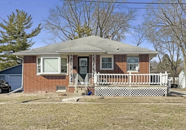 bungalow-style house with a garage, an outbuilding, brick siding, and a front yard