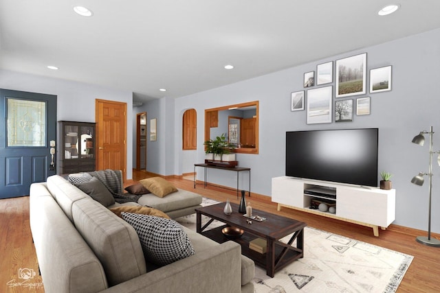 living room with arched walkways, recessed lighting, baseboards, and wood finished floors