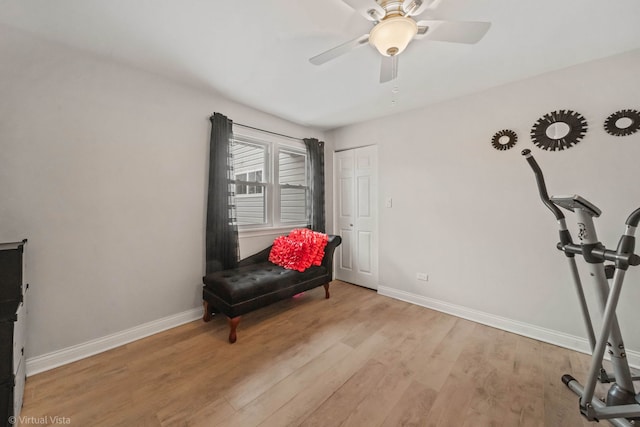 sitting room featuring baseboards, a ceiling fan, and light wood finished floors