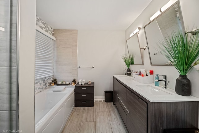 bathroom featuring visible vents, a sink, a tub with jets, double vanity, and baseboards