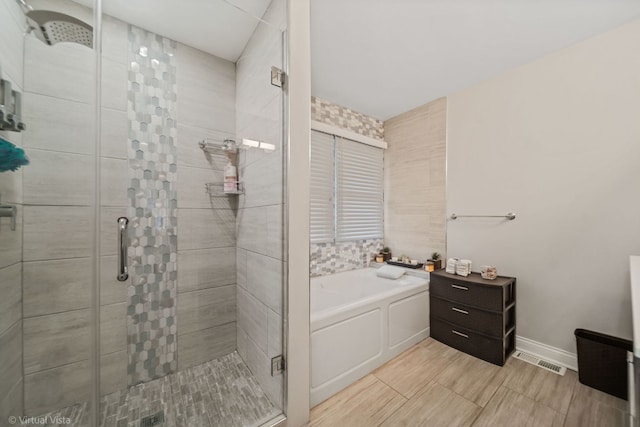 bathroom featuring visible vents, baseboards, a garden tub, and a shower stall